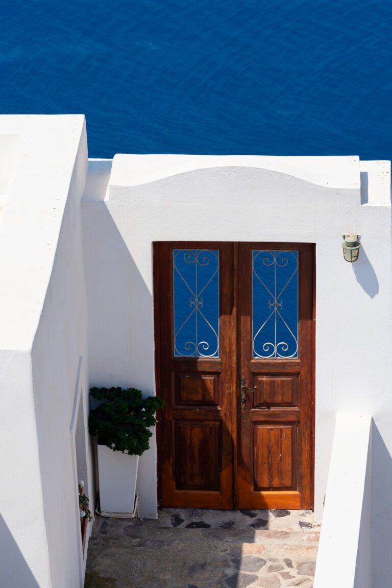 Puerta mediterránea de madera con detalles en forja, con vistas al mar mediterráneo.